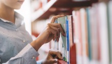 Woman at the library, she is searching books on the bookshelf and taking a textbook on the shelf, hand close up